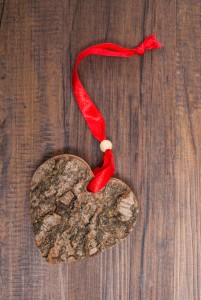 Wood with bark in heart shape and red ribbon on a board